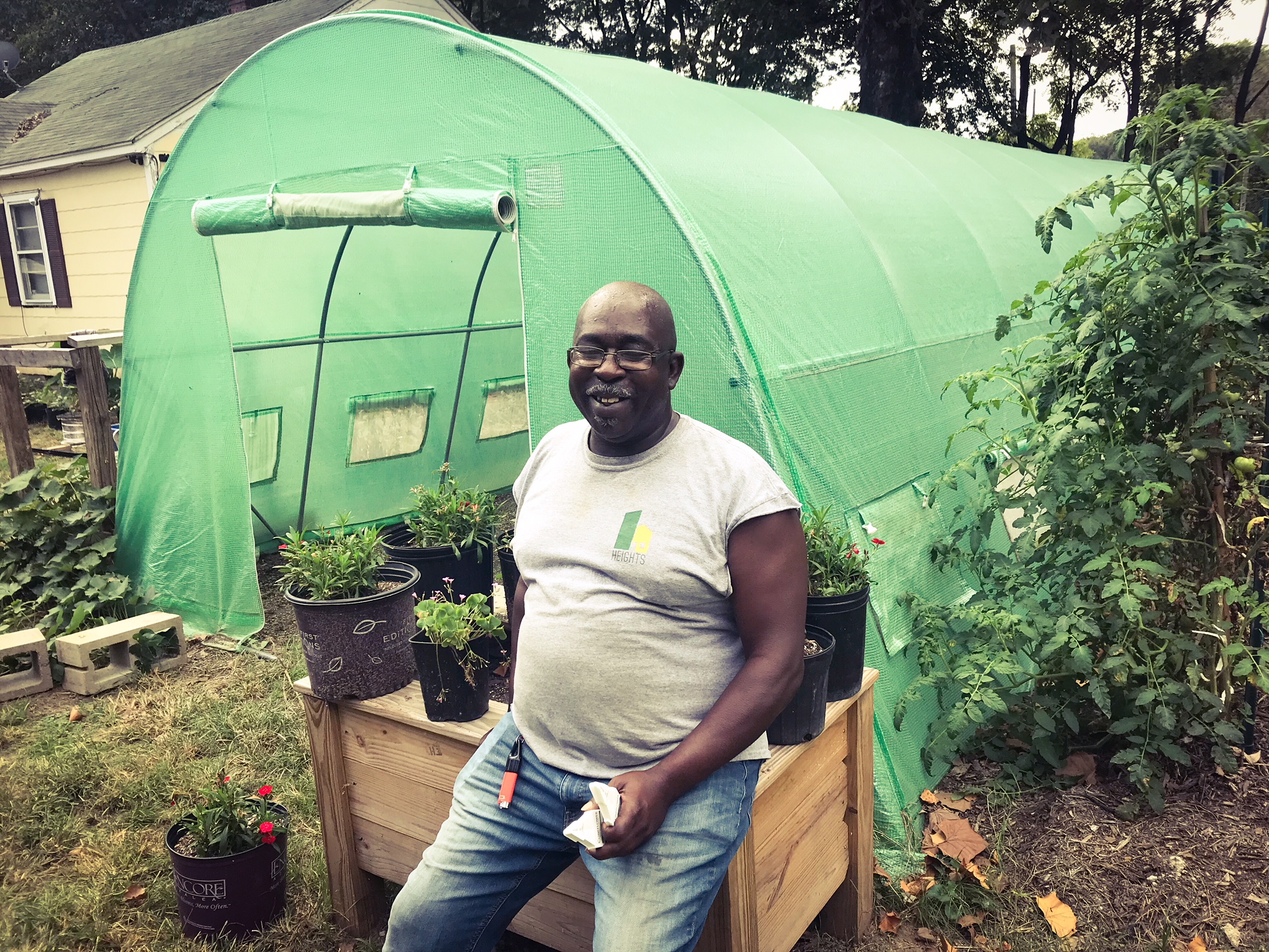 Sidney Johnson, president of the Mitchell Heights Neighborhood Association, poses in front of the hoop house at the Mitchell Heights Landscape Garden and Nursery. (Cole Bradley)