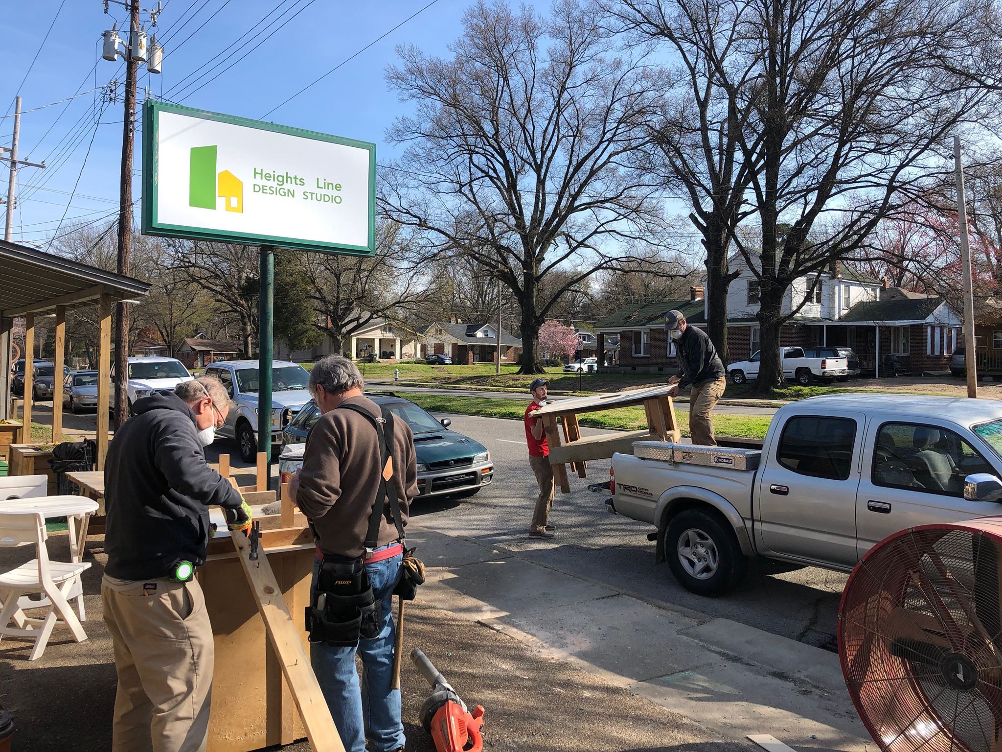 Ron Scott and Chris Clark prepare to install a door at the front of the workshop, as Tyler Parker and and Jared Myers load up a rickety work table that is no longer safe to use. All four are participants in the ad-hoc advisory board. (Scarlet Ponder)