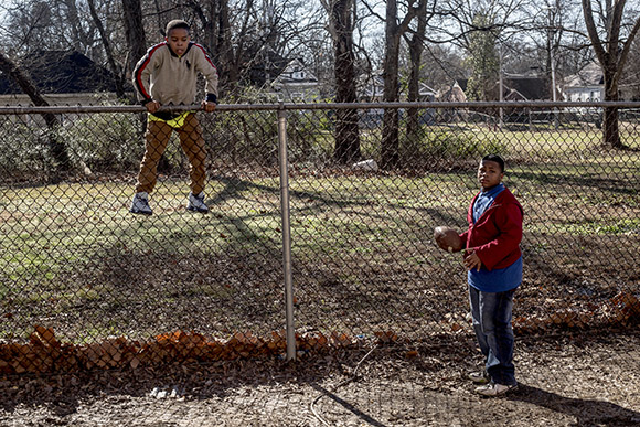 After retrieving a stray football from the next yard, a  student climbs back over the fence during recess at the Memphis Scholars Caldwell- Guthrie School in Smokey City.