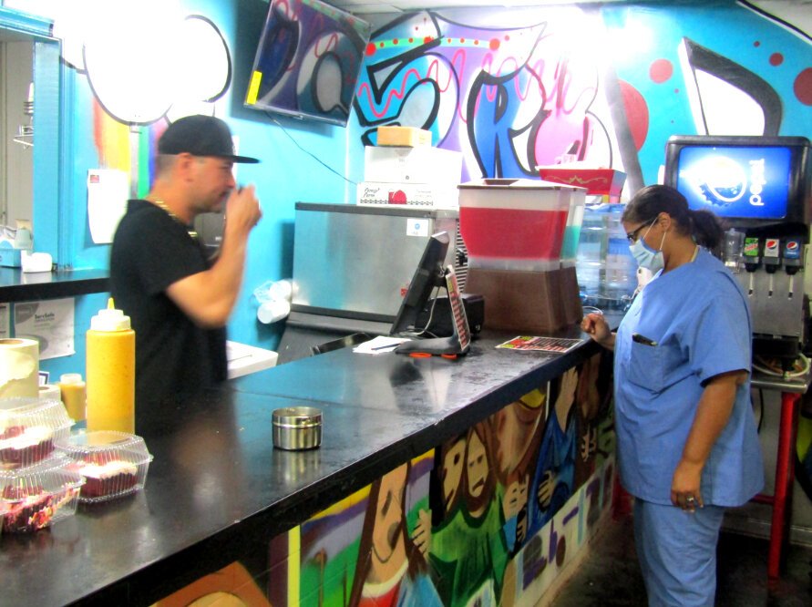 Customer Lasondra Boddie browses the menu at Straight Drop Seafood. Behind the counter, Ryan High waits to take her order. (Tamara Cunningham)