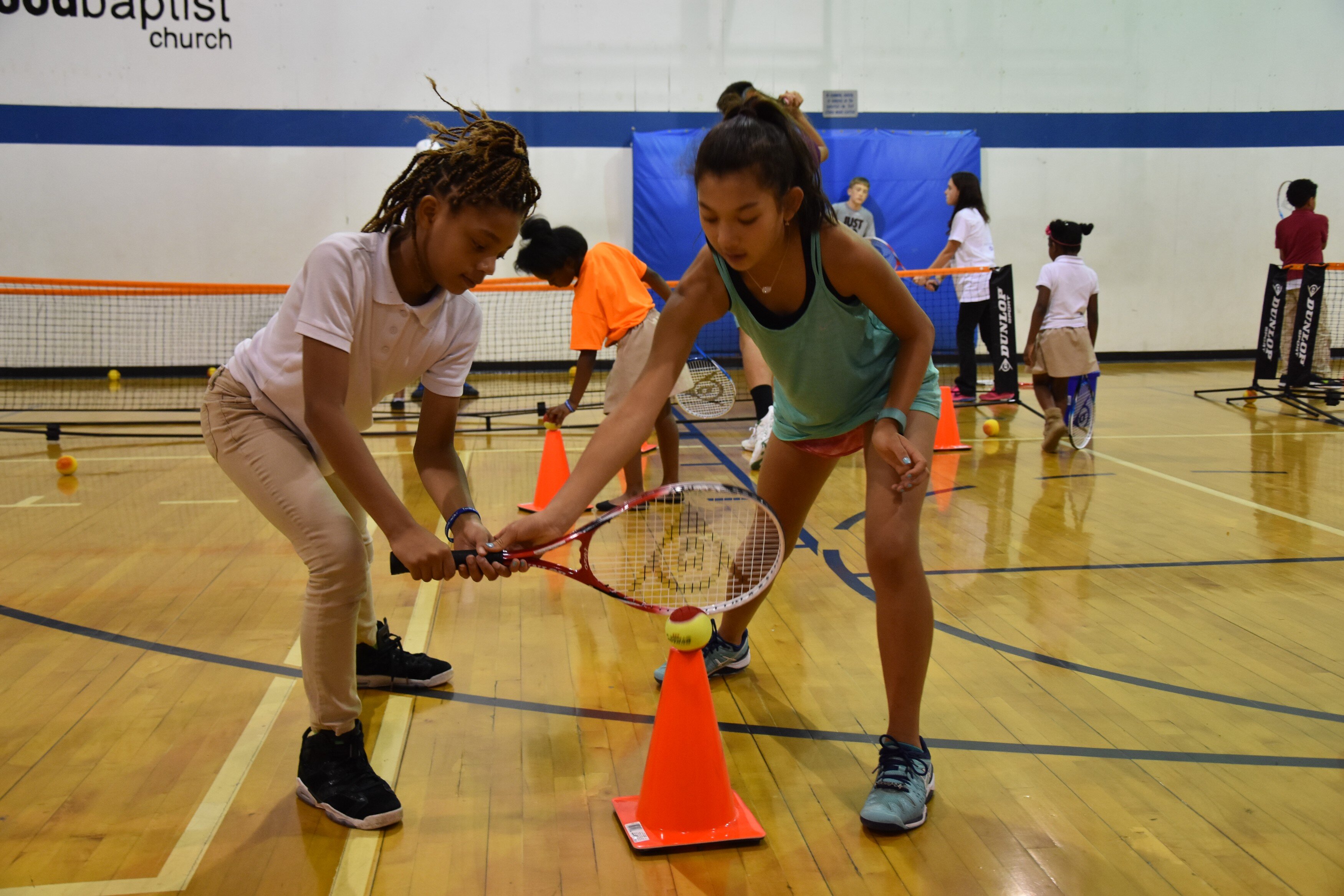 Ella DeJesus. right, helps a friend hone her tennis skills. Peer teaching is very important to Tennis Memphis because it is an effective way to build skills and friendships. (Tennis Memphis)